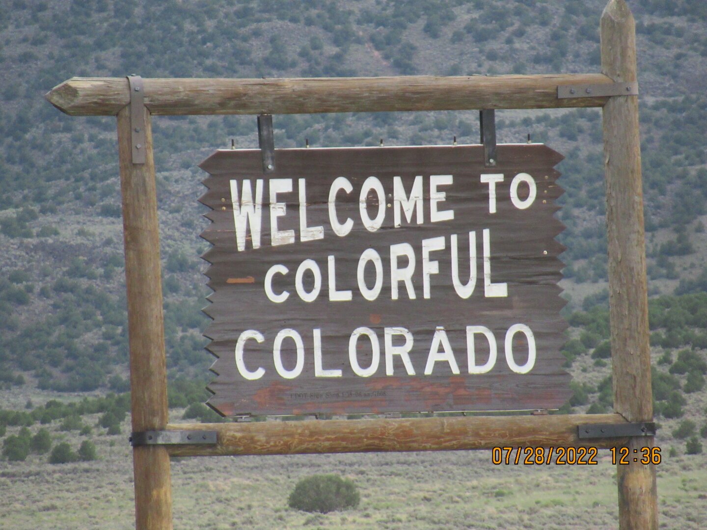 A wood sign, welcoming travelers to Colorado. Text on the sign: Welcome to Colorful Colorado.