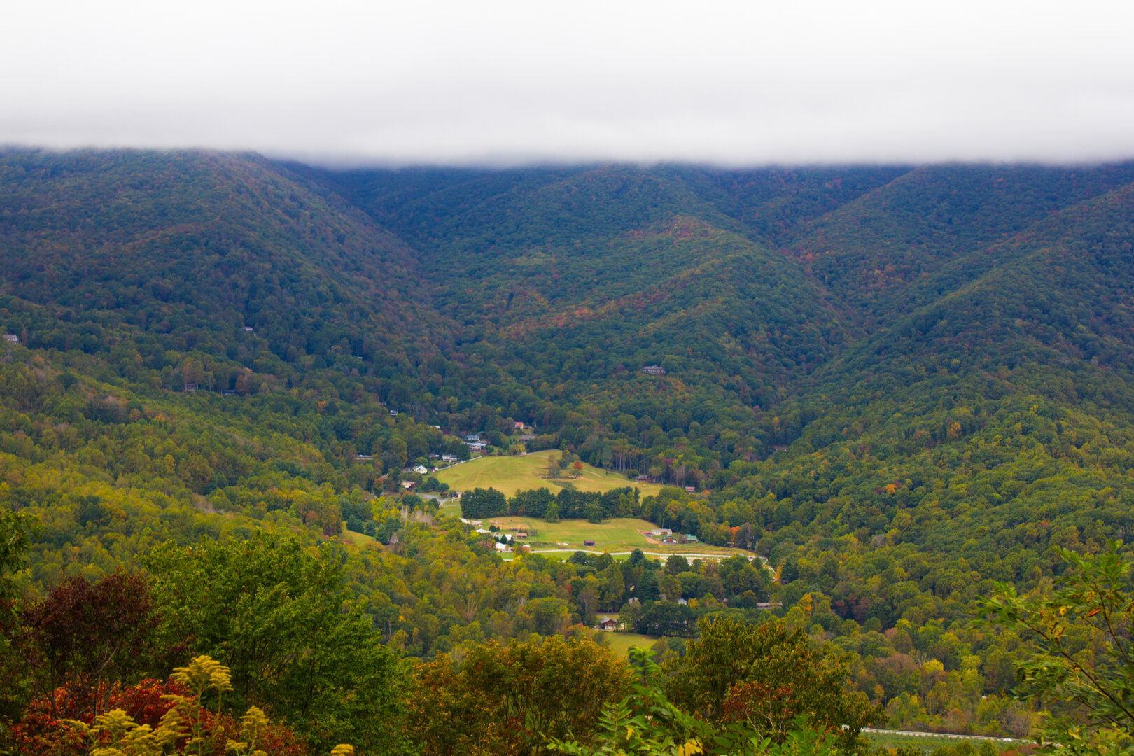 Before the Blue Ridge Parkway, a small town called Maggie Valley sits in the dip of the green bushels of rolling countryside and forest. A cloud cover is above the range.