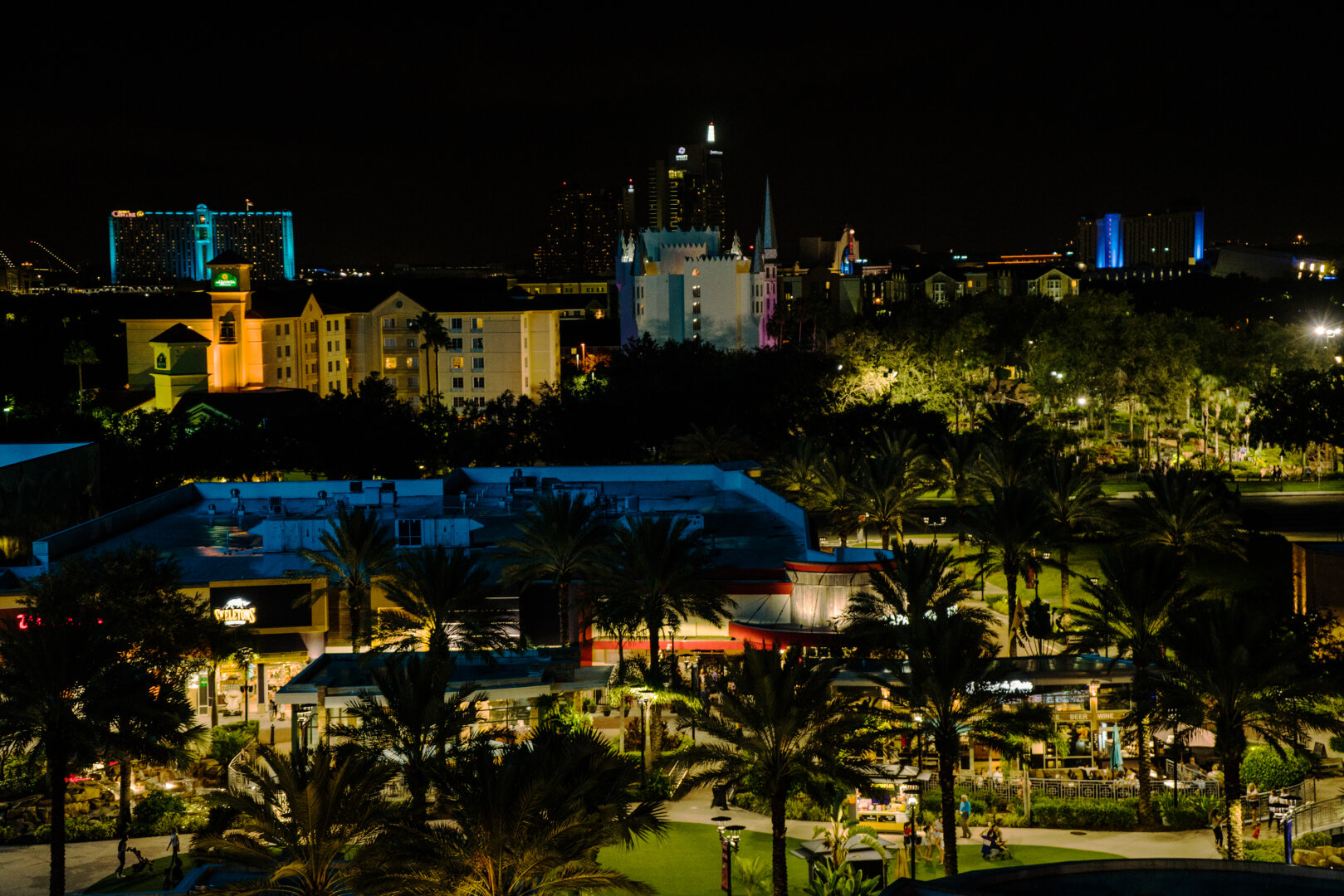 I-drive is bright during the night time with warm and blue lighting throughout the landscape. Palm trees peak out through the shadows.