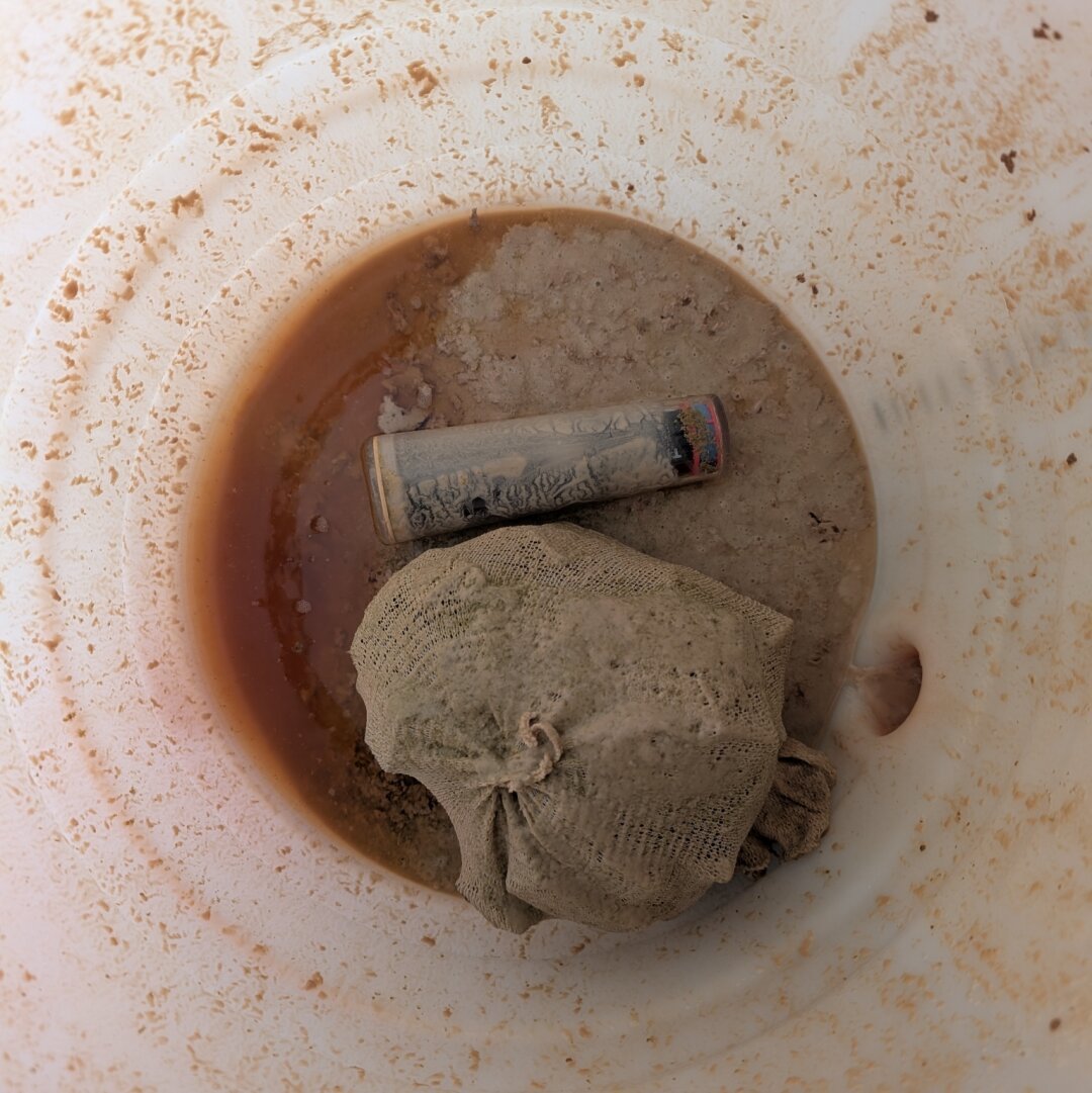 Ein Gärfass von innen mit Heferesten, Hopfensäckchen und iSpindel.