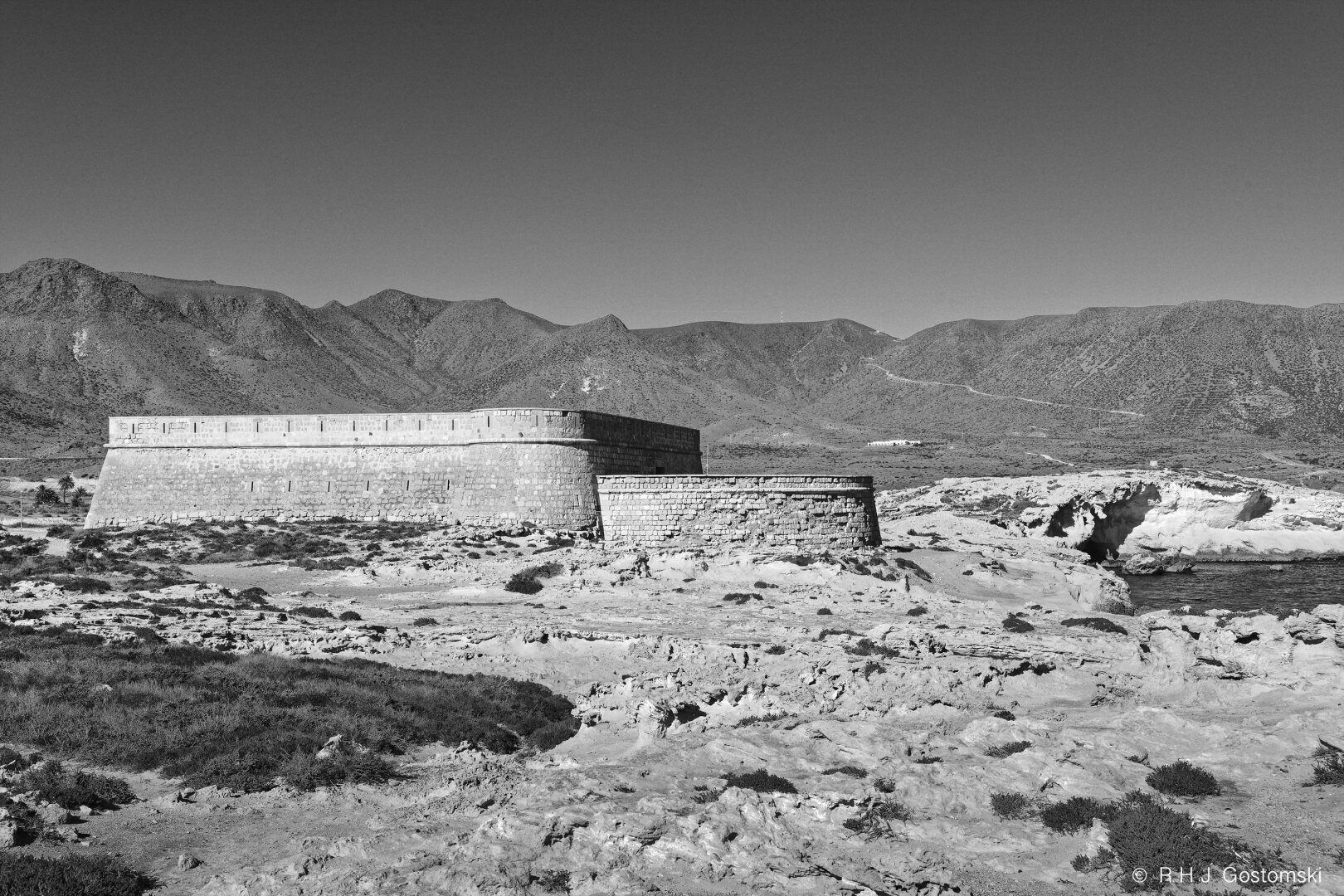 Black-and-white photograph of Castillo de San Felipe o de los Escullos on the coast with a sea view behind