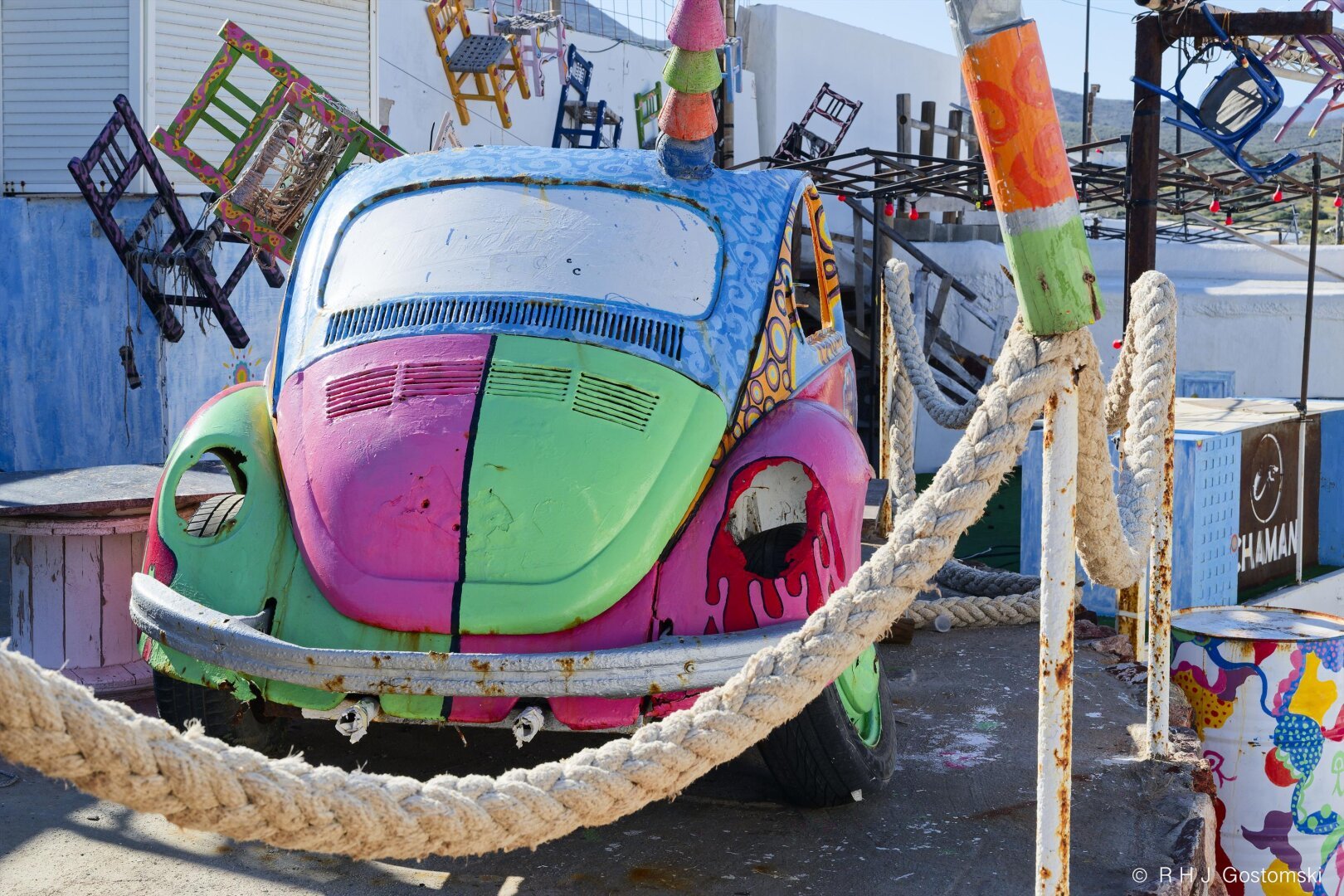 An old VW Beetle brightly painted in a mix of vivid colours and used as a decorative feature in a beach bar/restaurant