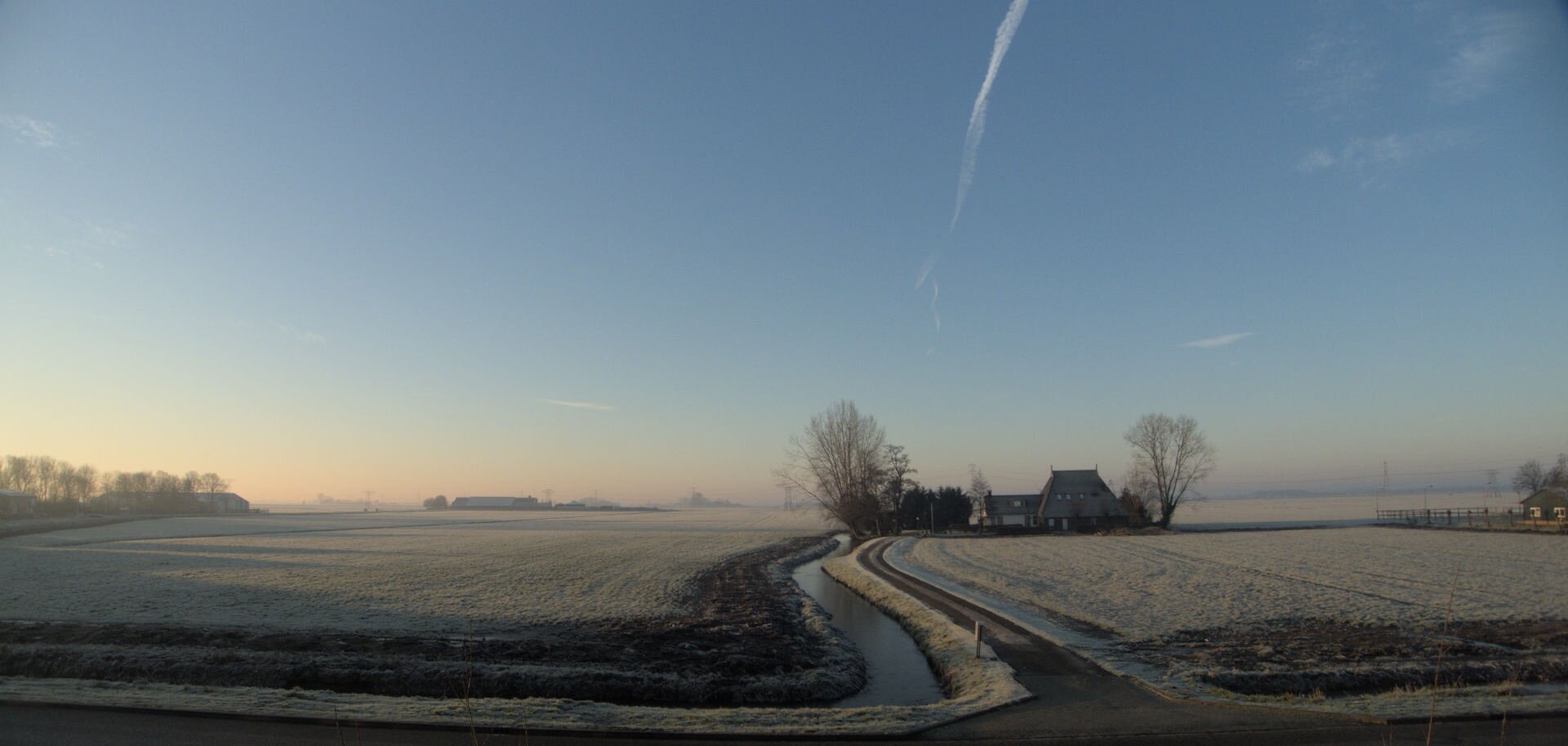 view of the graslands at the other side of the road all in white - and the farmers house in the middle