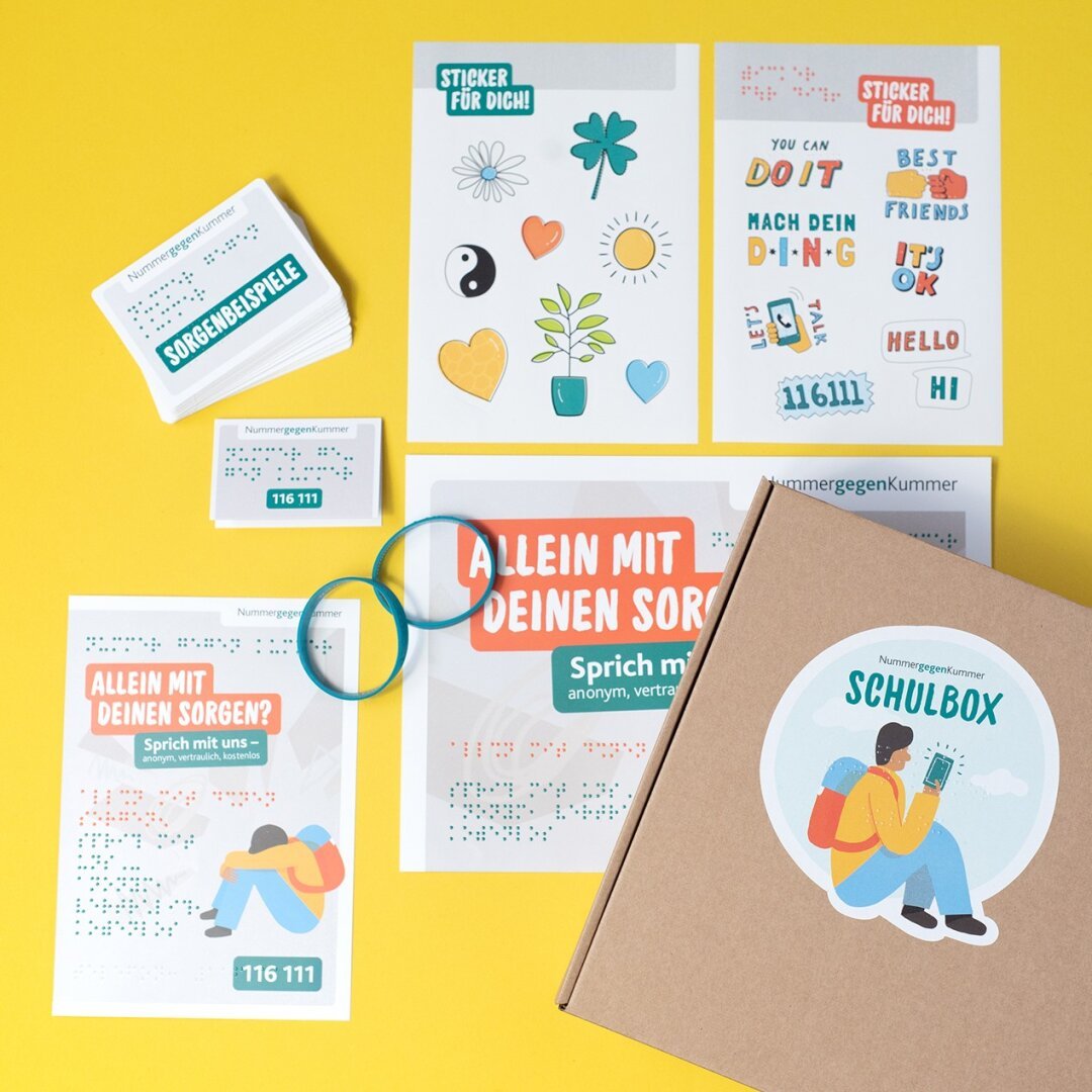 Auf einem gelben Untergrund liegen alle Materialien inklusiven Schulbox: Flyer, Poster, Sticker, Infokarten, Armbänder und Karten mit Sorgenbeispielen.