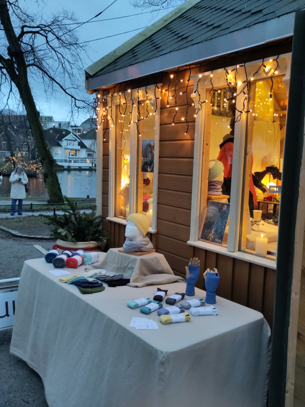 A wooden Christmas market house with a table with different wares in front.