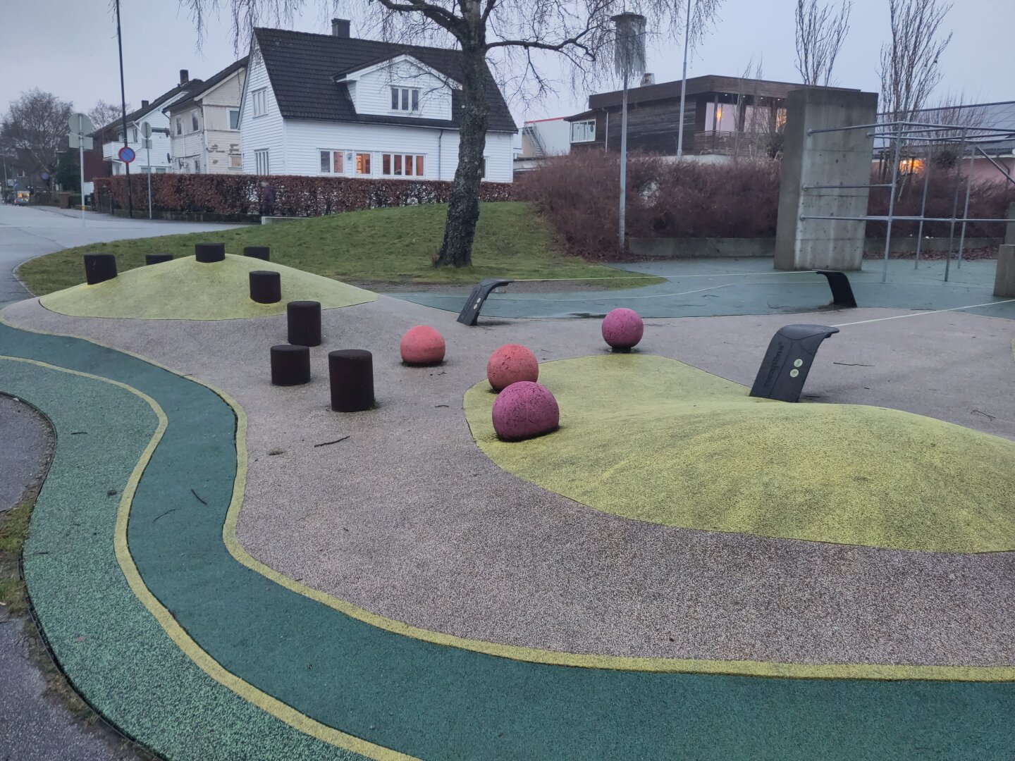 A playground in grey, yellow-green and green colours with different balancing items, like red bslls, blackncolumns and tightropes.