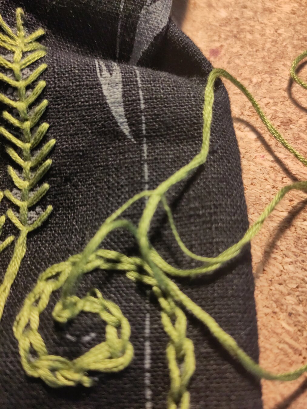 Green embroidery where a bundle of threads has splitted another thread