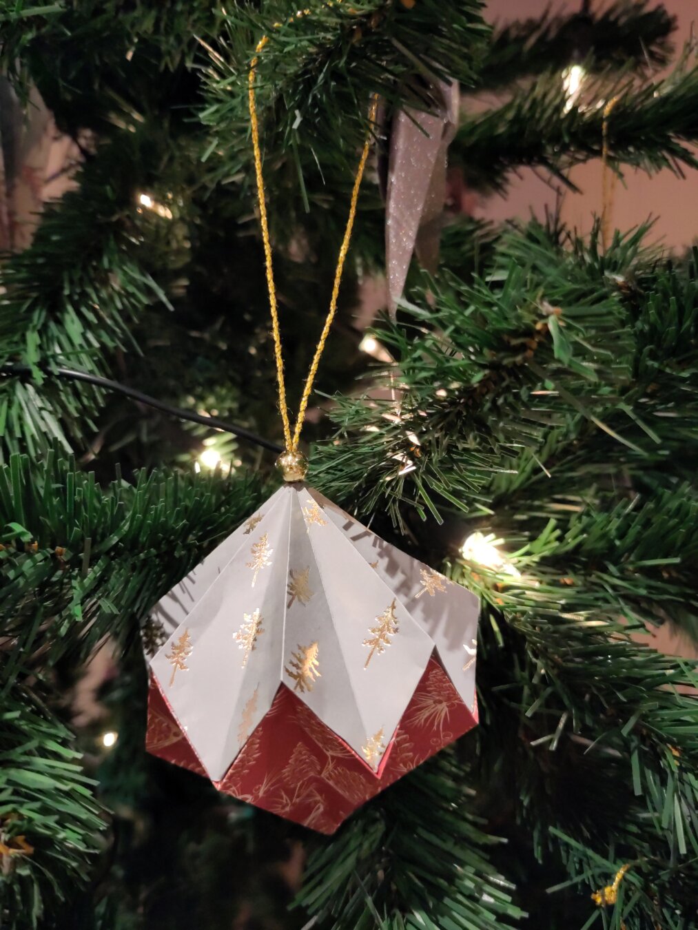 A modular origami ornament in a Christmas tree made of red paper and light blue paper with golden trees