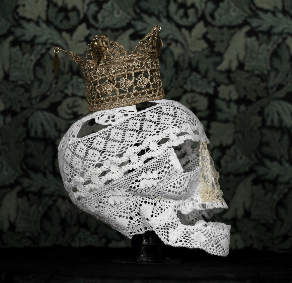 A skull made of white lace, wearing a golden crown, also made of lace.