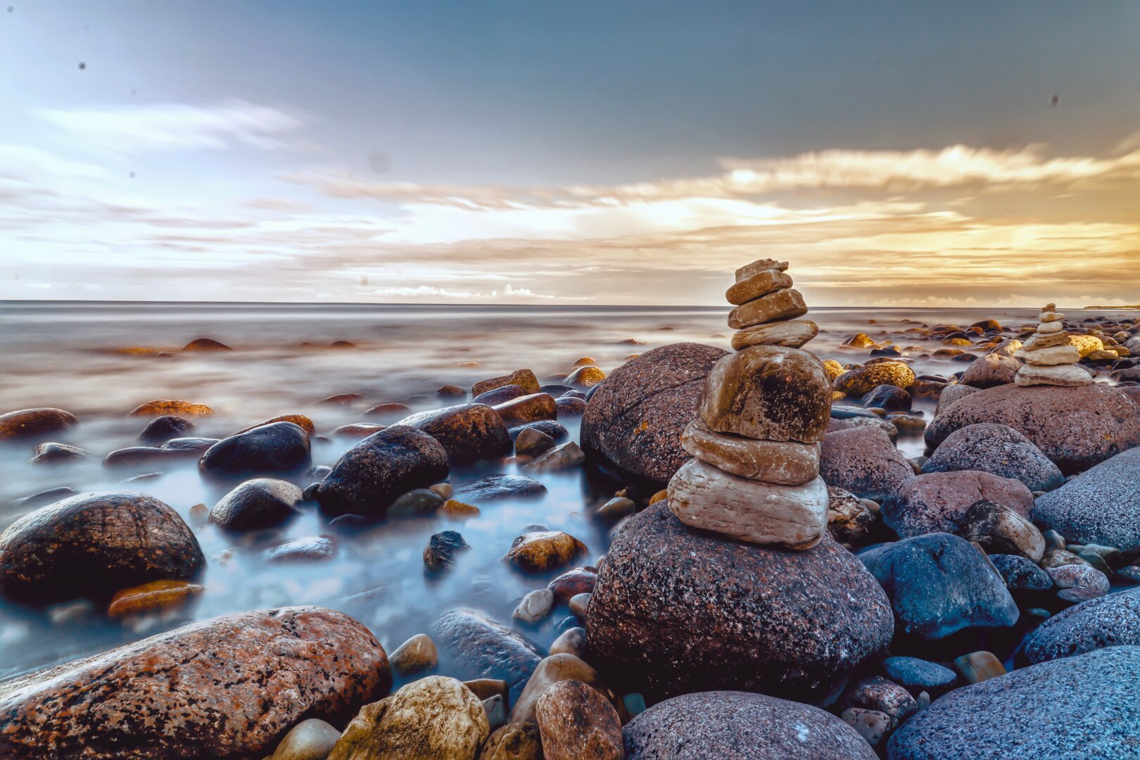 A long exposure of a rocky beach under the sunset.