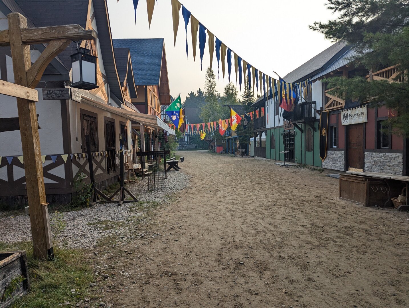 Medieval village with blue and yellow banners crossing over a dirt road