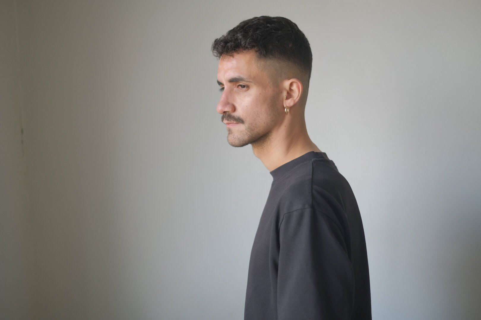 Autoportrait de profil sur un fond blanc. Je porte un t-shirt noir.