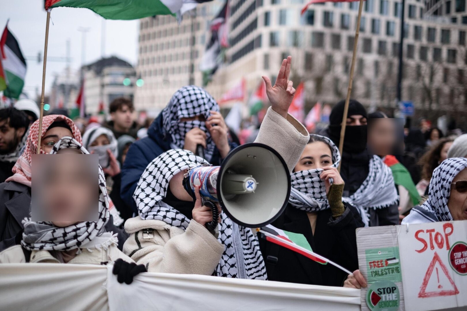 Cortège de tête. Toutes les personnes portent un keffieh. La personne au centre scandé dans un mégaphone.