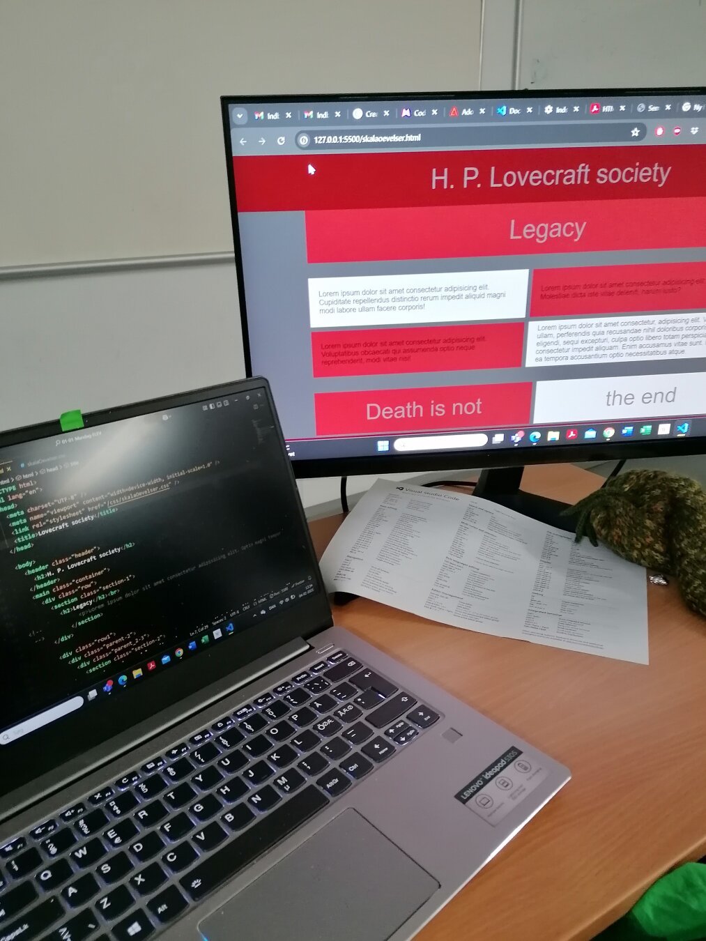 To the left a laptop is showing html code, on the right is a screen showing the result of the code.
The test wep page is shown in gray and red, with the heading "H. P. Lovecraft society"