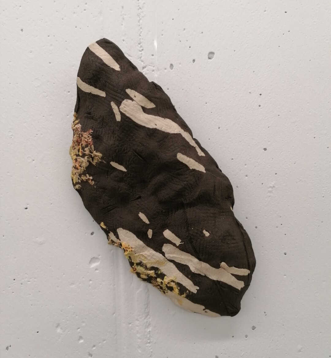 Stentøjsler moduleret til at ligne lavbegroet rombeporfyr med en stof pregning I overfladen.

Stonewear clay shaped to look like the stone type rombeporfyr.