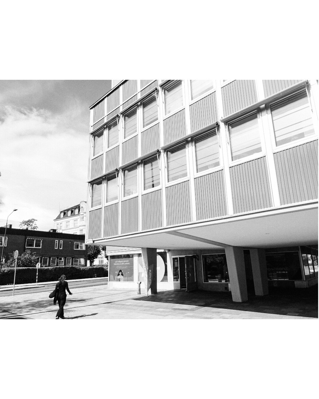 Low-angle architectural view of a concrete overhang with a person walking beneath it.