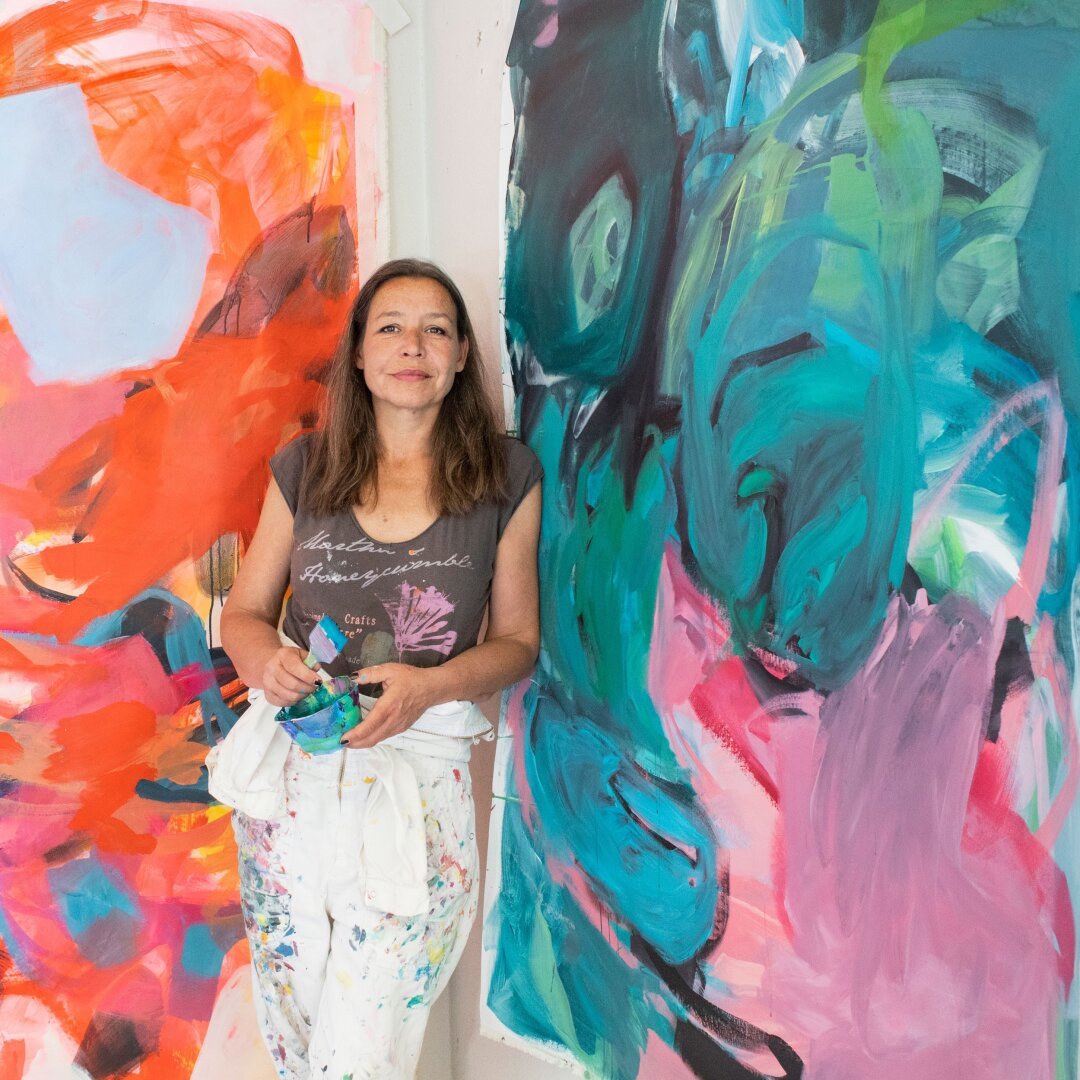 Artist in front of large abstract paintings