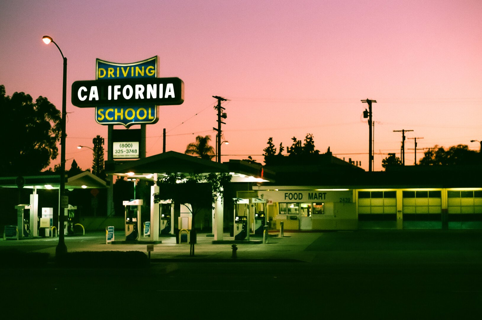 Photo of a gas station at sunset with a sign saying “California driving school”