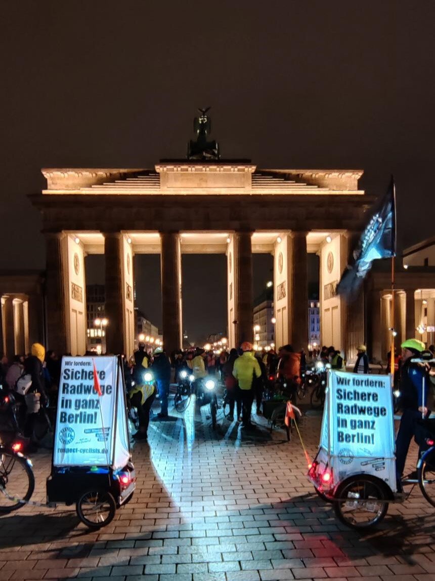 Auf der Rückseite des Brandenburger Tors hat sich eine große Gruppe Radfahrender zu einer Kundgebung versammelt.
Im Vordergrund sind zwei