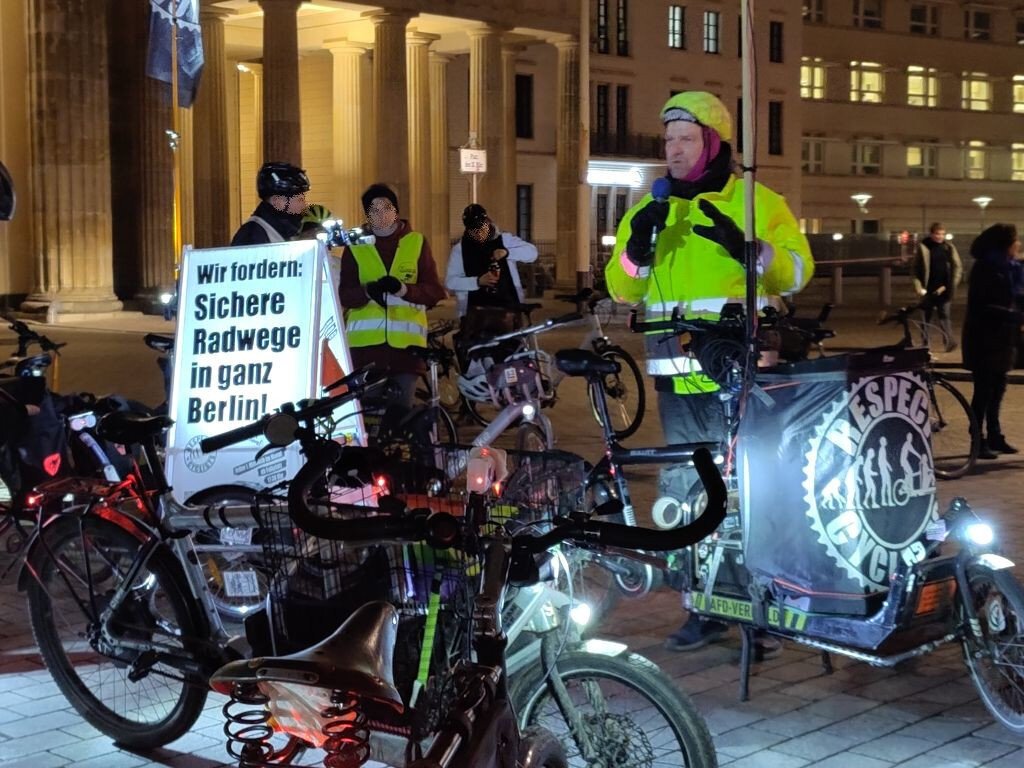 Jörg von den Respect Cyclists steht hinter seinem Lastenrad und spricht ins Mikrofon. Auf dem Lastenrad eine Lautsprecherbox, die mit einer