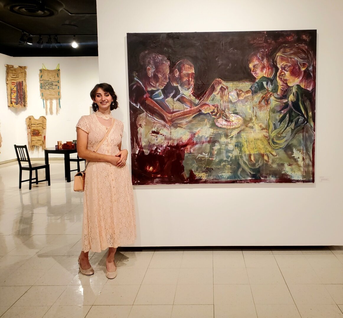 Woman standing next to a large painting