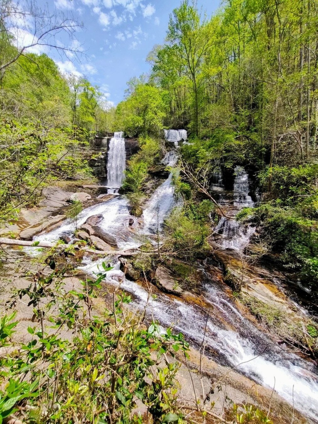 A striking photo of three different waterfalls rushing over the cliff face converging into the stream below.