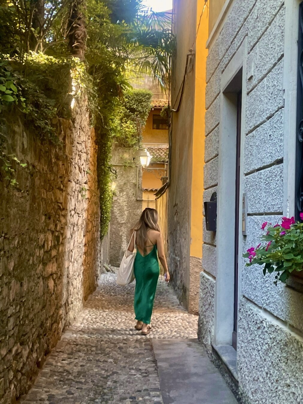 Walking down a street in Bellagio, Italy. Woman wearing green dress stepping on cobblestone.