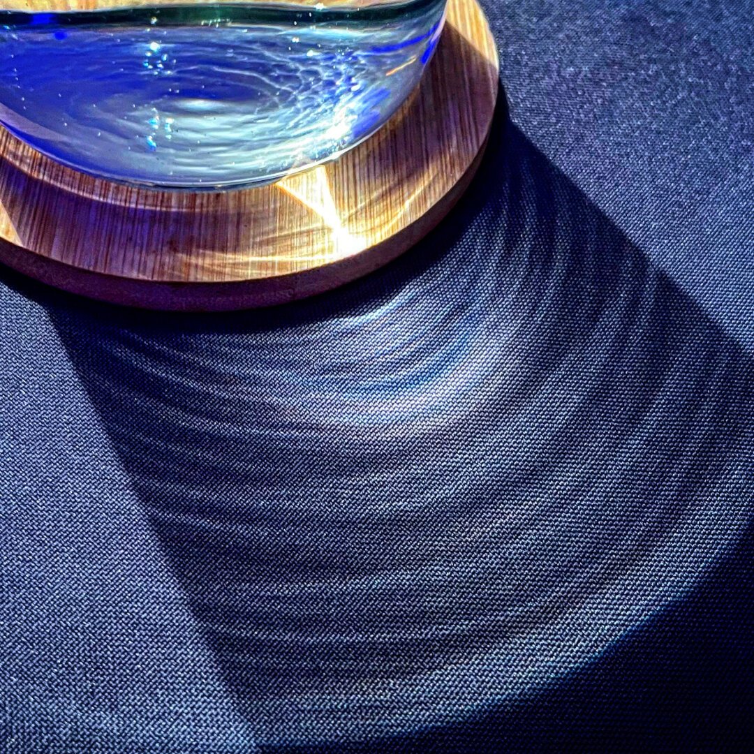 Light refraction through a water bottle in the form of ripples on a tablecloth.