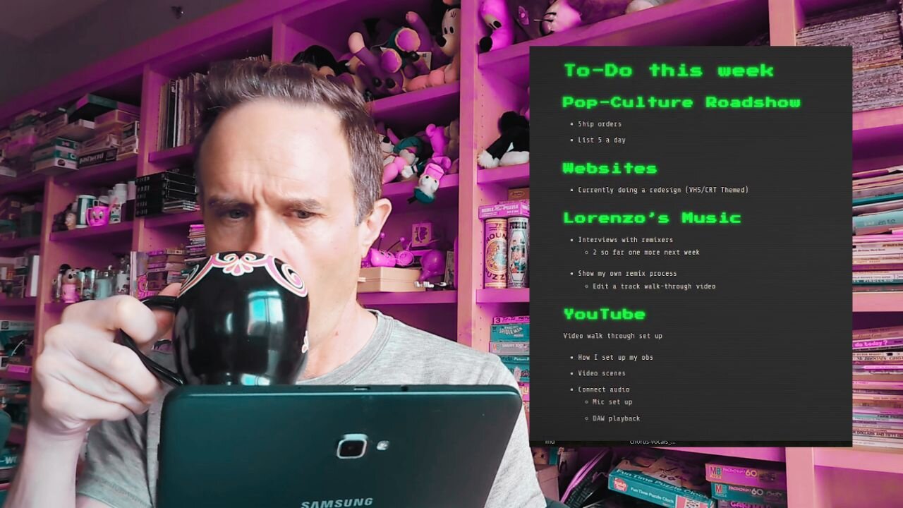 person drinking out of a mug, looking at a tablet