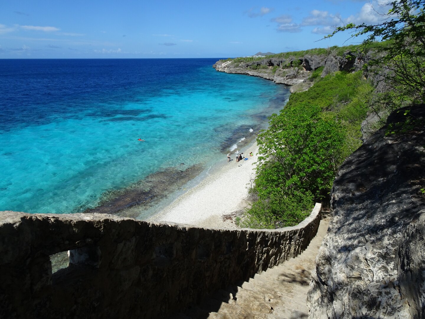 A stair leading down to a beach with crystal clear water.