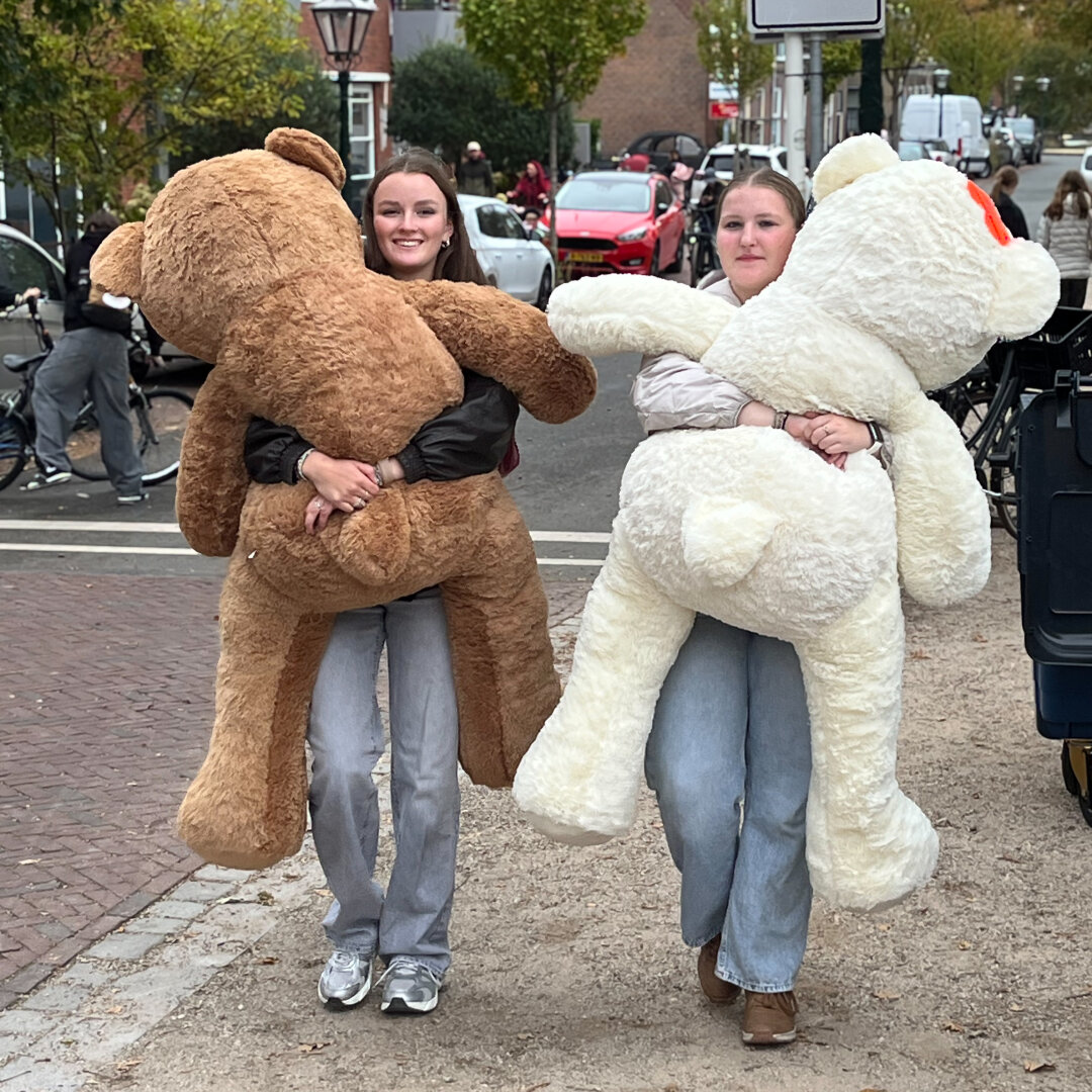 Two walking girls each carrying a big bear
