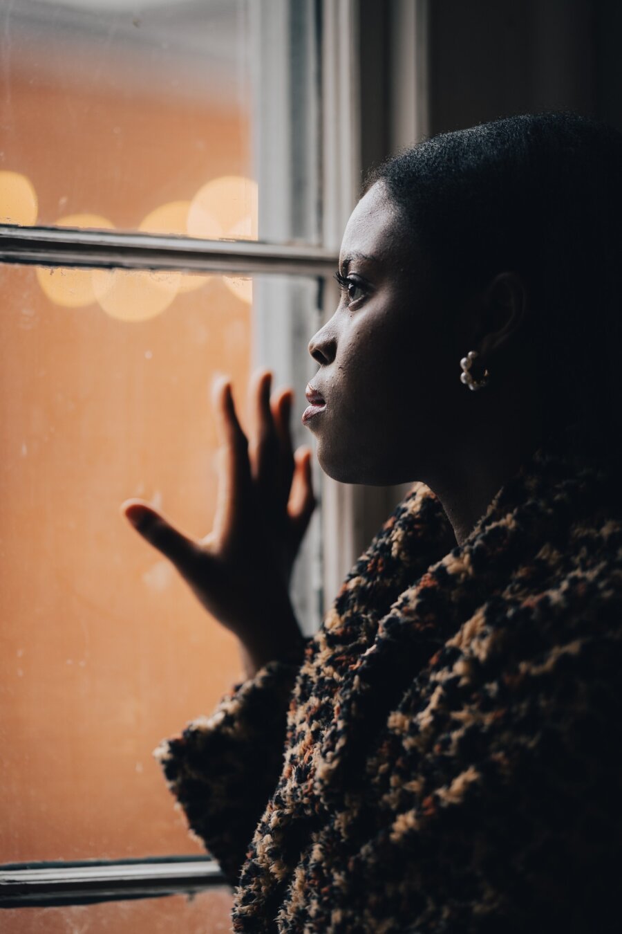 Profile image of a woman looking out a window on a cold, winter day.