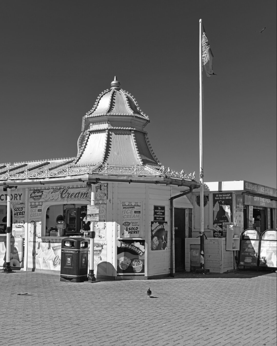 Monochrome photo of a seaside kiosk selling ice-cream. Late C19, formerly part of the original Aquarium (by Eugenius Birch) and re-sited here c.1927. Included in the Grade 2* listing. City of Brighton & Hove, UK.