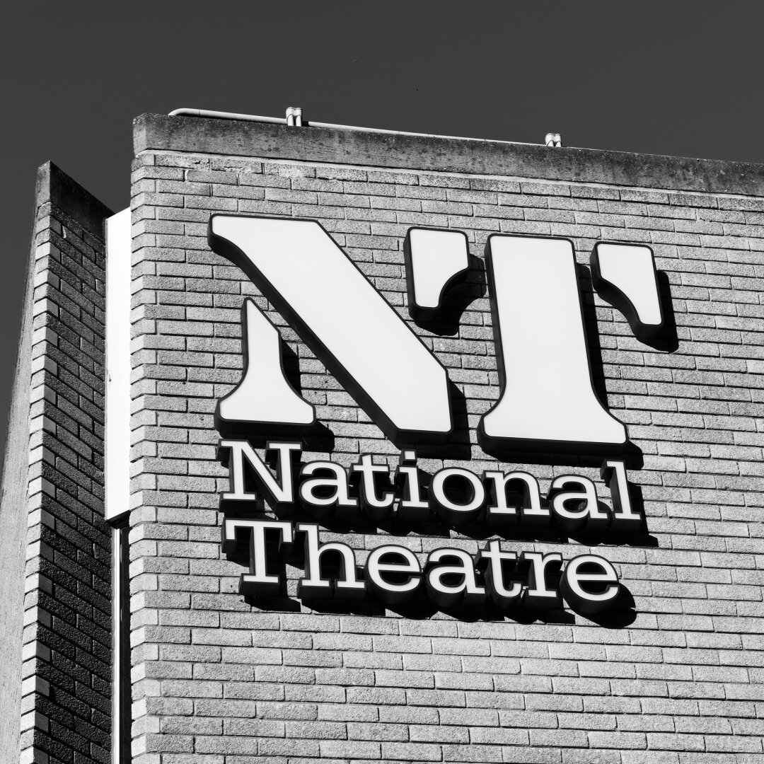 Monochrome photo looking up at London's National Theare logo  designed 1974 by Ian Dennis while working at FHK Henrion's London studio. National Theatre opened 1976. Grade 2* listed.  South Bank, London Borough of Lambeth
