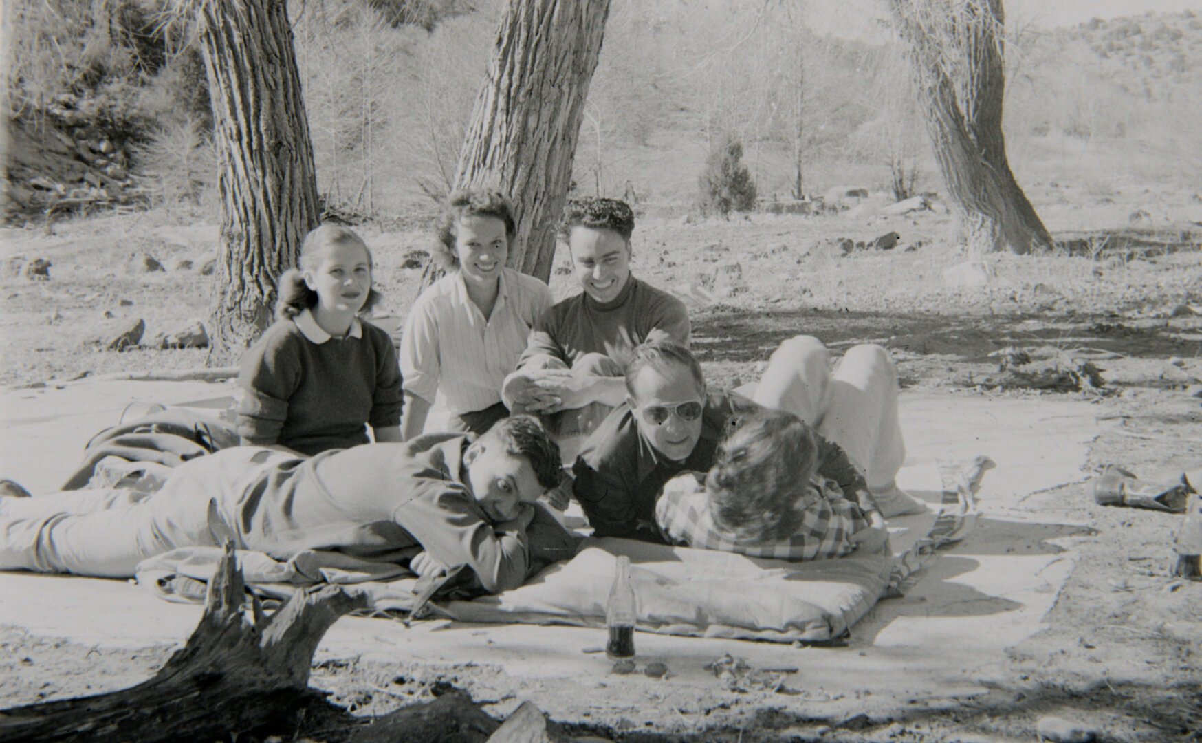 A group of young people sit on a blanket