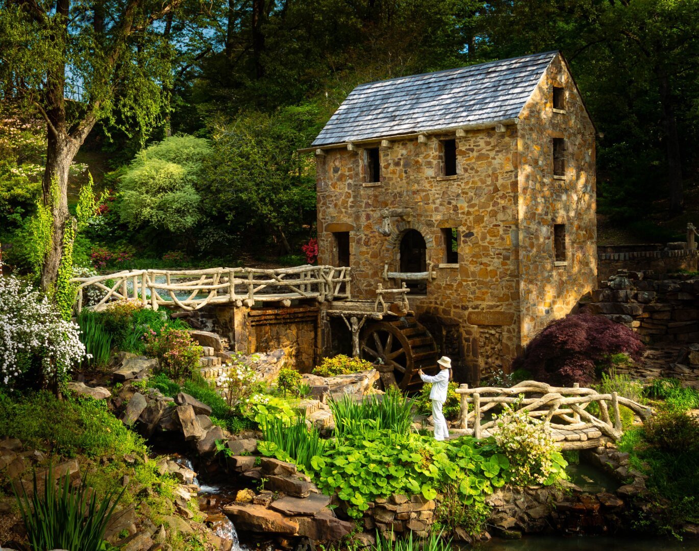 Woman takes a selfie in front of an old mill in garden like surroundings.