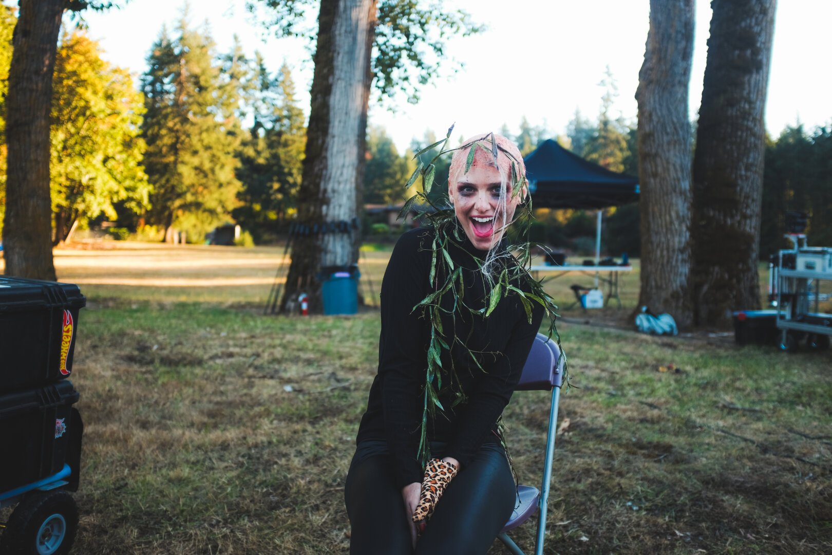Actress Emily Sweet gives a big smile as she sits outside in a park on a sunny day, getting her makeup finished before heading to set