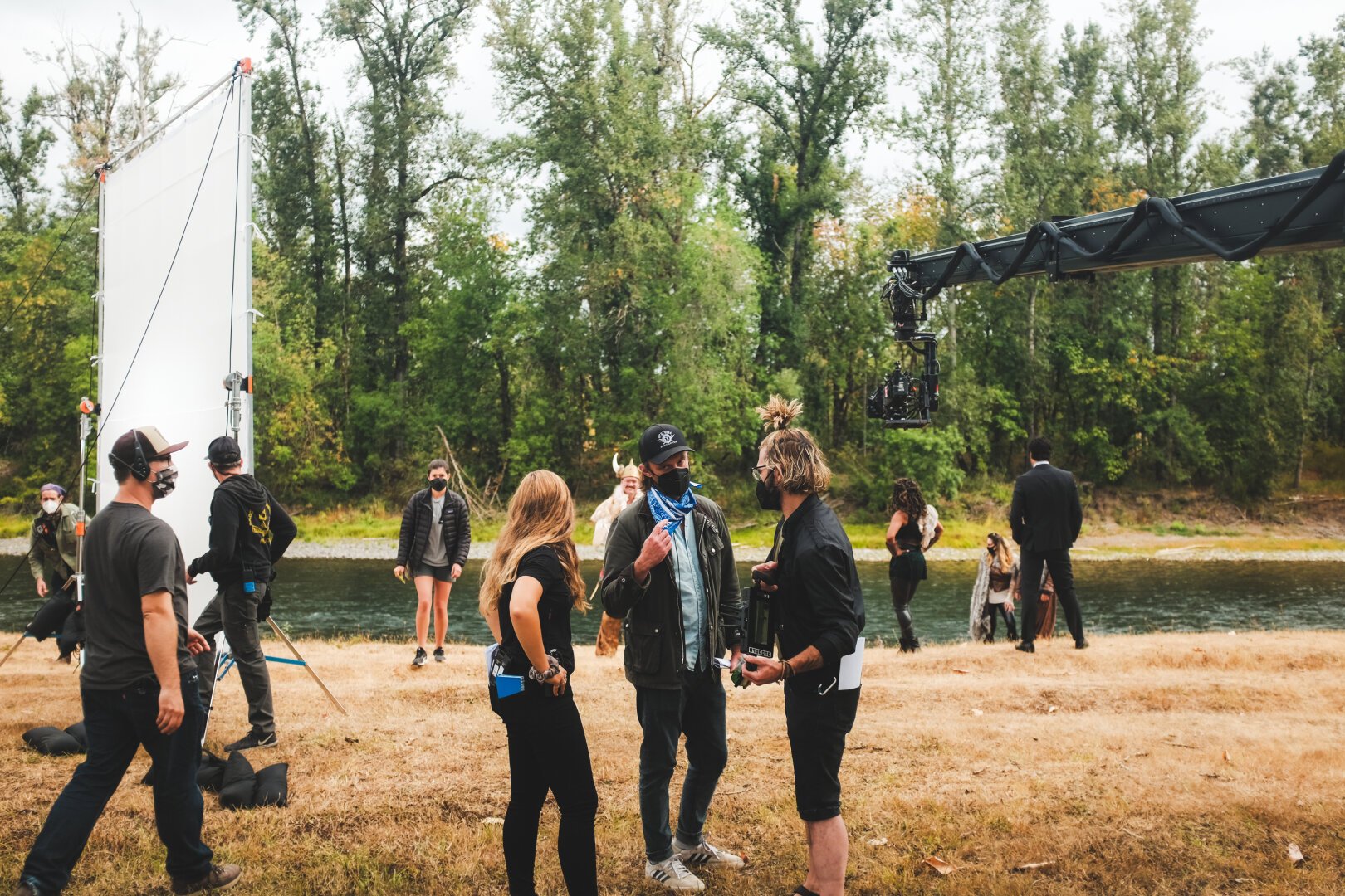 Crew members talk on the set of a movie. To the left is a 15-20ft ultra bounce, on the right, a camera sits on a jibarm