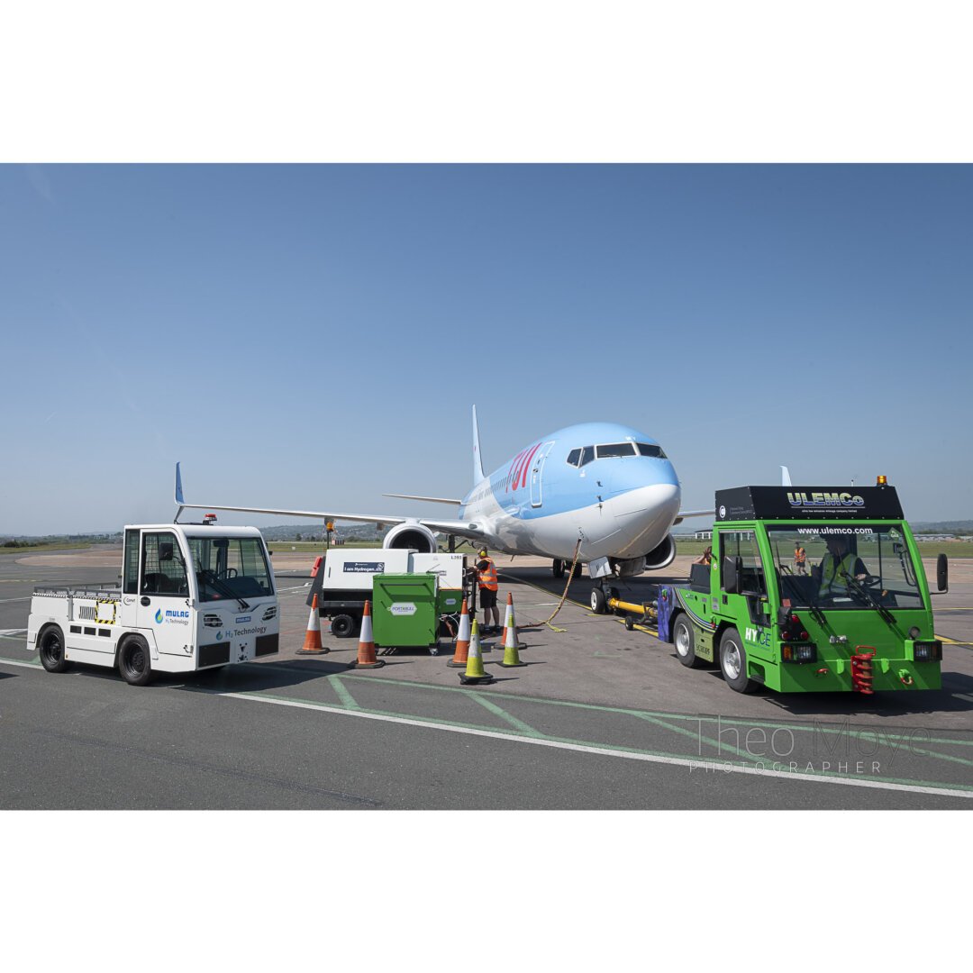 A luggage tractor, and ground-power unit and aircraft tug, all powered by hydrogen, stand in front of a Boeing 737