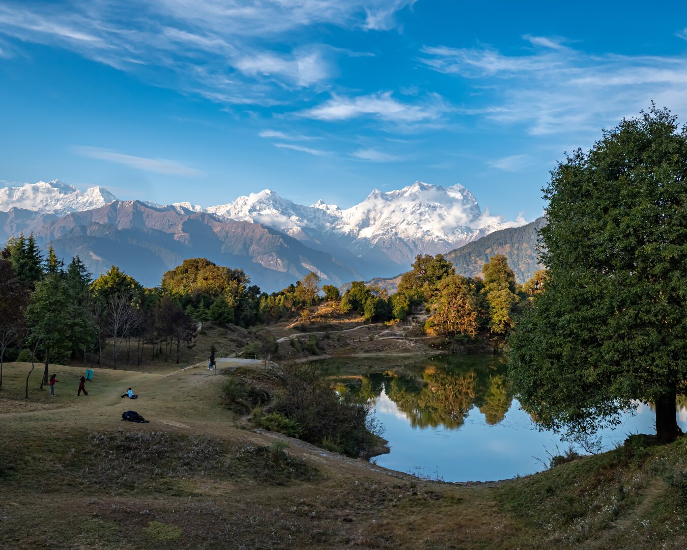 Snow mountains with scattered clouds and blue sky seen from a lake side in a beautiful valley