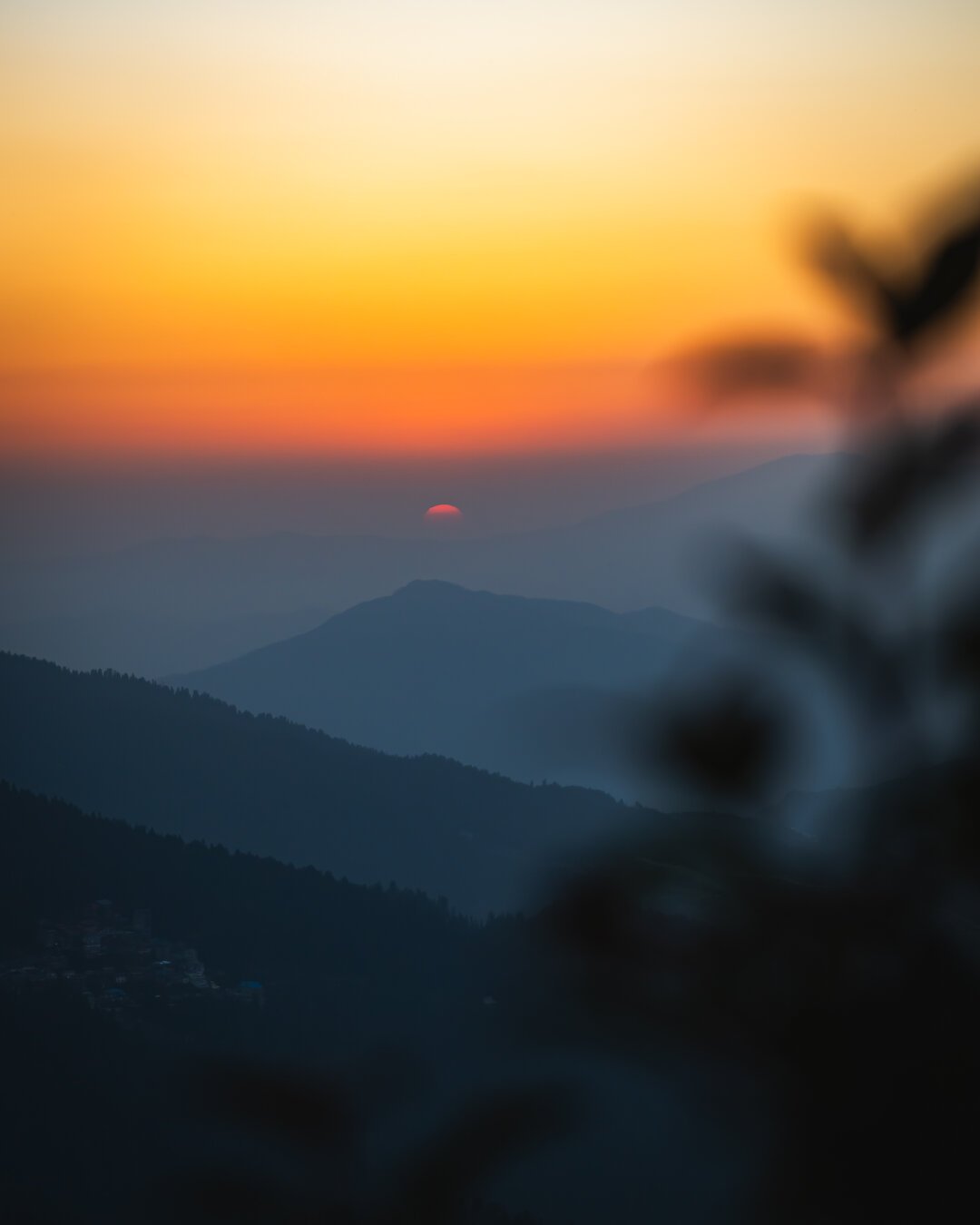 Sun setting over valley in the distance with red yellow silhoutte in the sky
