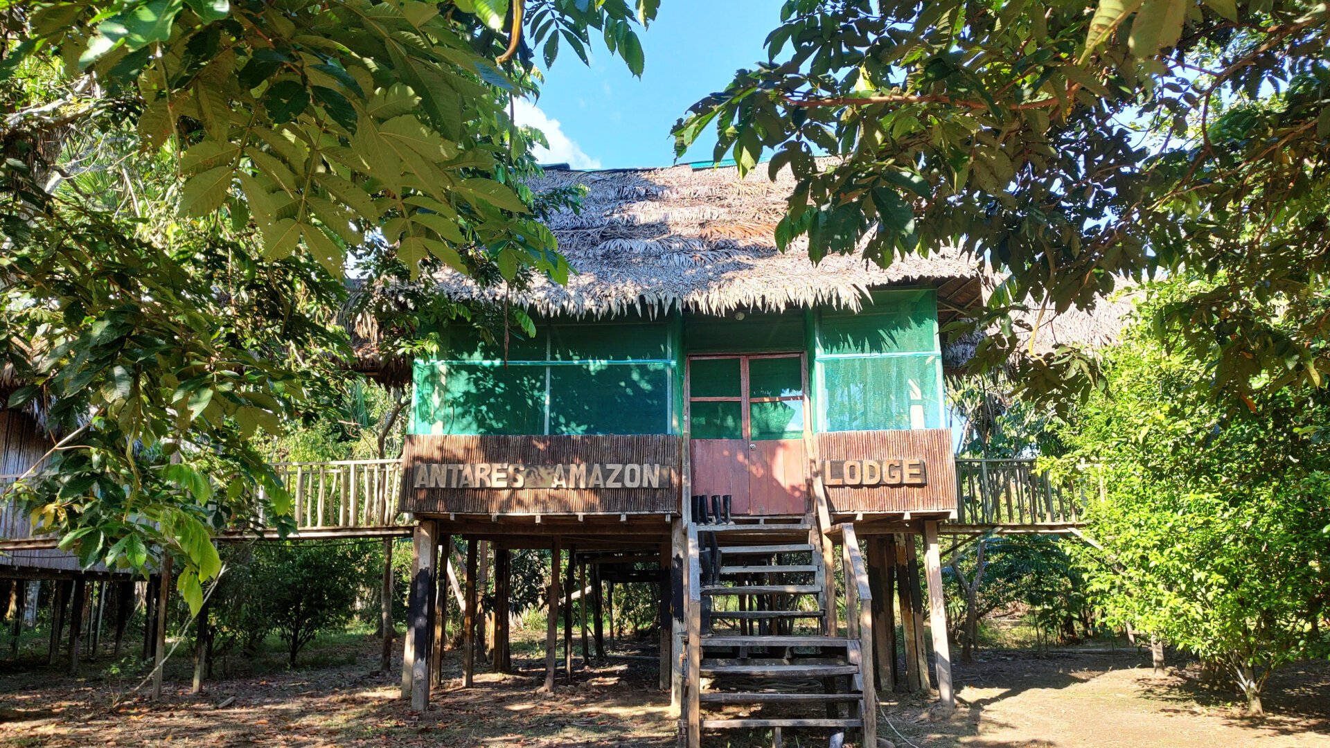 The main building of the lodge. Also a simple hut on stilts. A staircase with several steps leads up to the entrance door. To the left and right of the building, footbridges lead to other parts of the lodge.