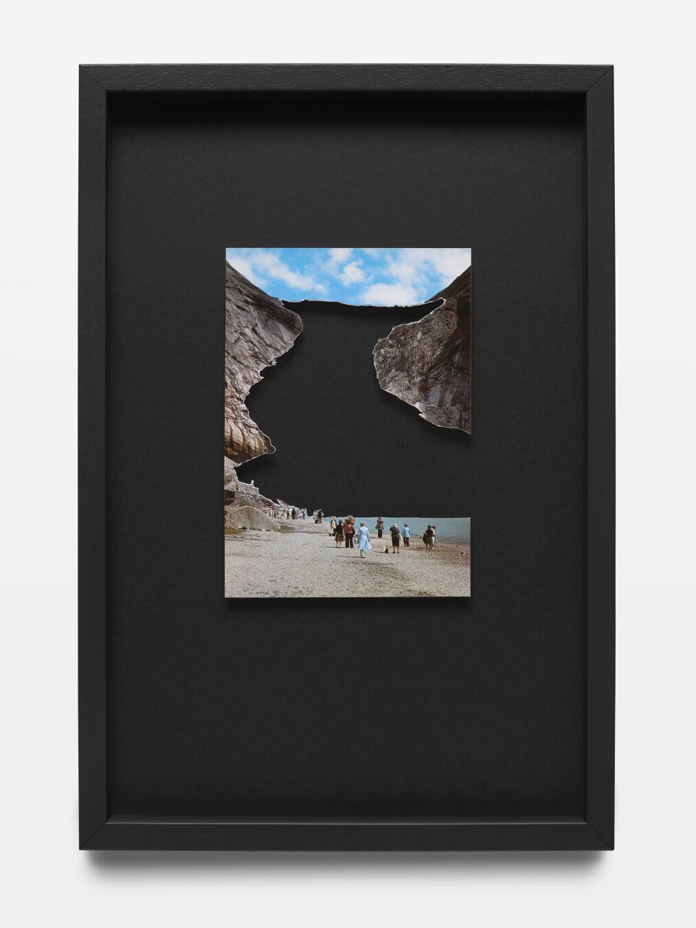 We see a black wooden frame displaying a postcard showing the Brixdalsbreen glacier in Norway. The glacier itself has been cut out from the postard, only a black void is left.