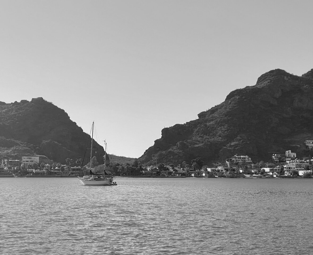 Sailboat anchored with desert mountains behind