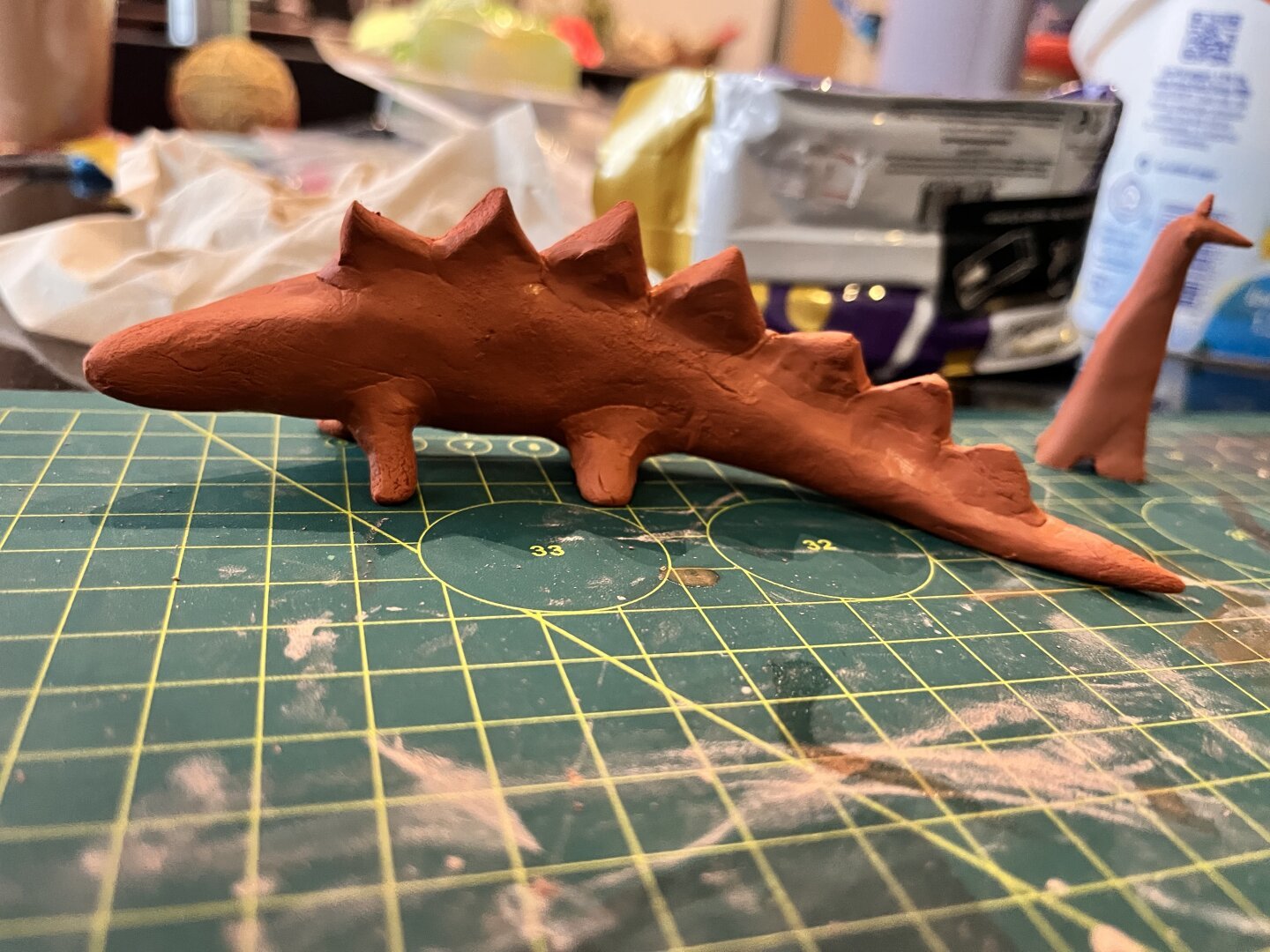 A clay stegosaurus, terracotta in color