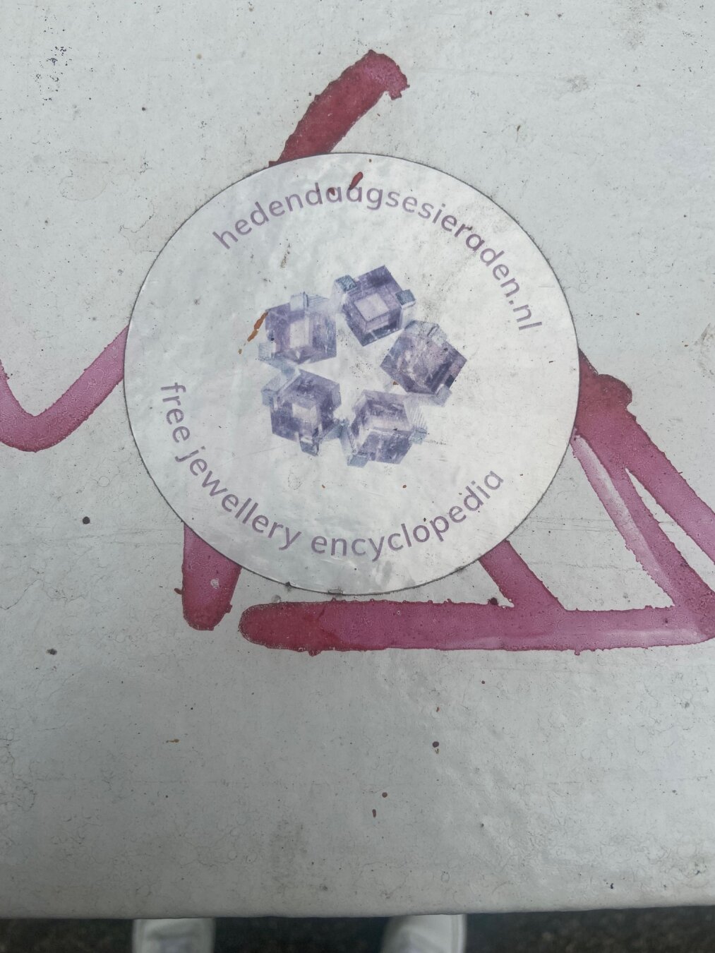 Ronde sticker van hedendaagsesieraden.nl op grafitti.