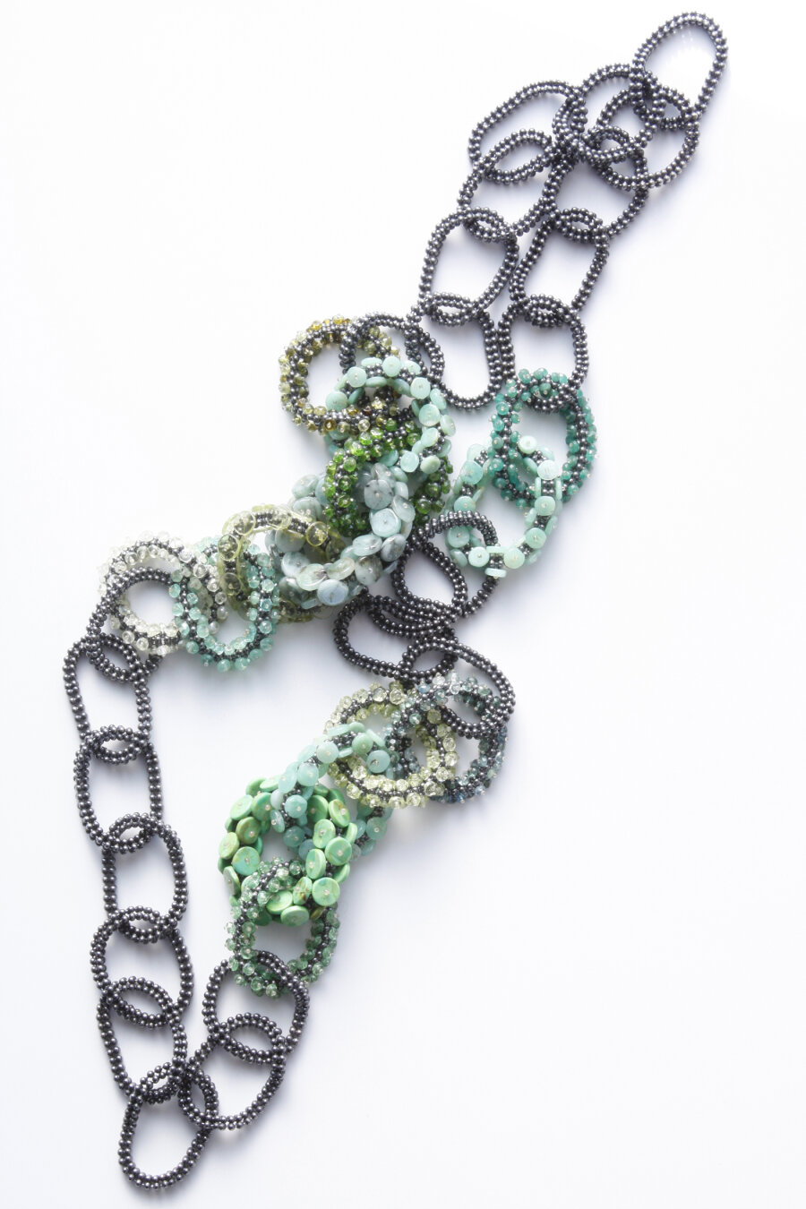 Halssieraad met van elkaar verschillende ovale schakels die zijn samengesteld uit kralen in groen, grijs en wit.