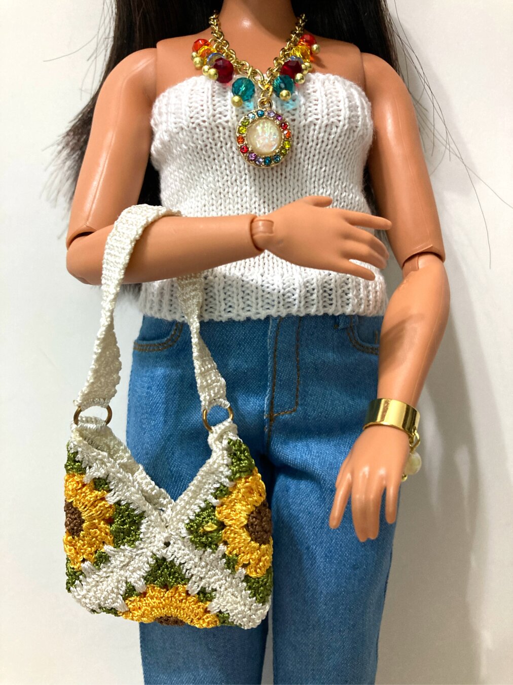 Picture of the body of the doll in the last picture cropped at the neck and knees. It was taken head-on. The right arm is lowered to waist height, still holding the shoulder bag at the elbow by the strap.