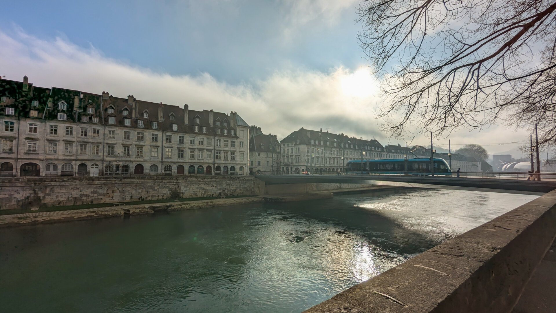 Dock of a River (Doubs) in Besancon, sun is shining behind clouds