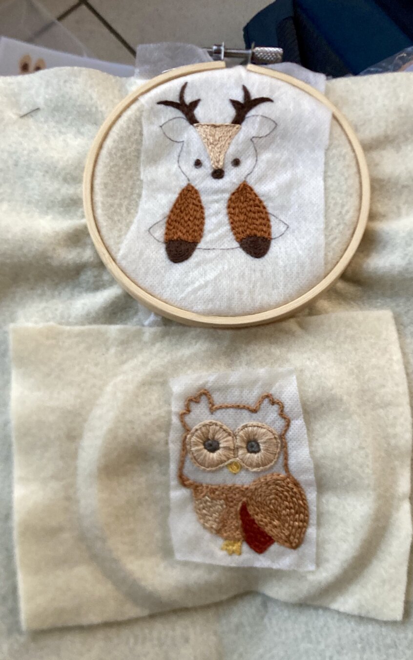 Photo de la petite chouette brodée du post précédent (pas encore terminée, il lui manque les plumes de la face)et juste au dessus, encore dans le cercle à broder, un petit cervidé en cours de brodage dans différents fils marrons sur de la feutrine beige.